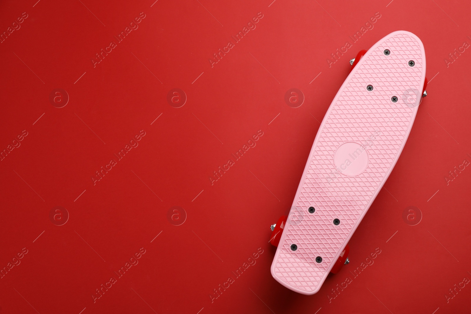 Photo of Skateboard on red background, top view. Space for text