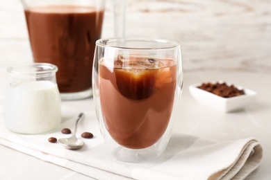 Glass with cold brew coffee and beans on table