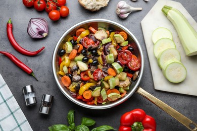 Photo of Flat lay composition with delicious cooked vegetables in pan and fresh ingredients on grey table