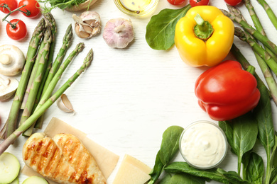 Photo of Frame made with asparagus and products on white wooden table, flat lay. Space for text