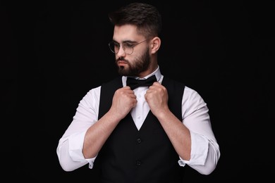 Portrait of handsome man in shirt and bow tie on black background