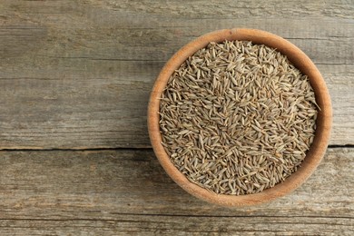 Photo of Bowl of caraway seeds on wooden table, top view. Space for text