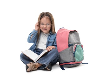 Cute little girl with book and backpack on white background