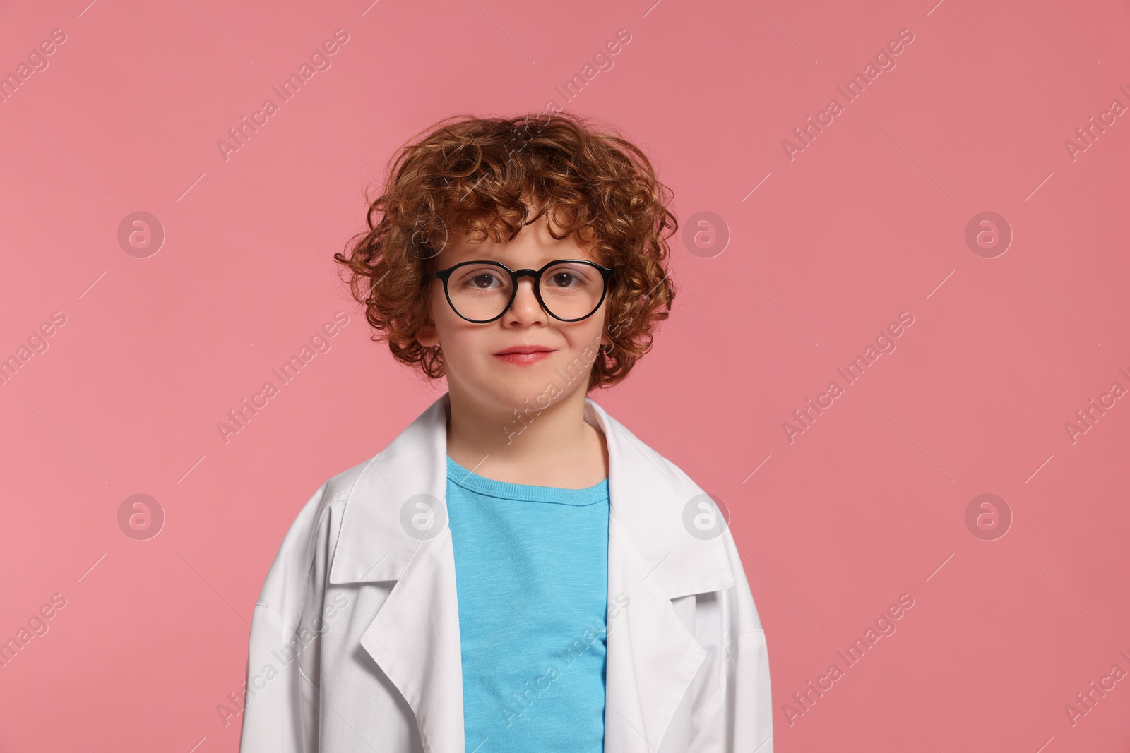 Photo of Portrait of little boy in medical uniform and glasses on pink background