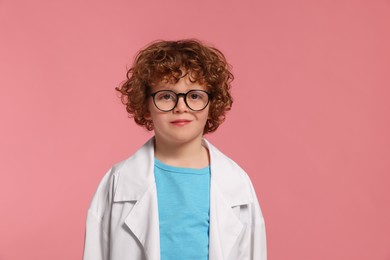 Photo of Portrait of little boy in medical uniform and glasses on pink background