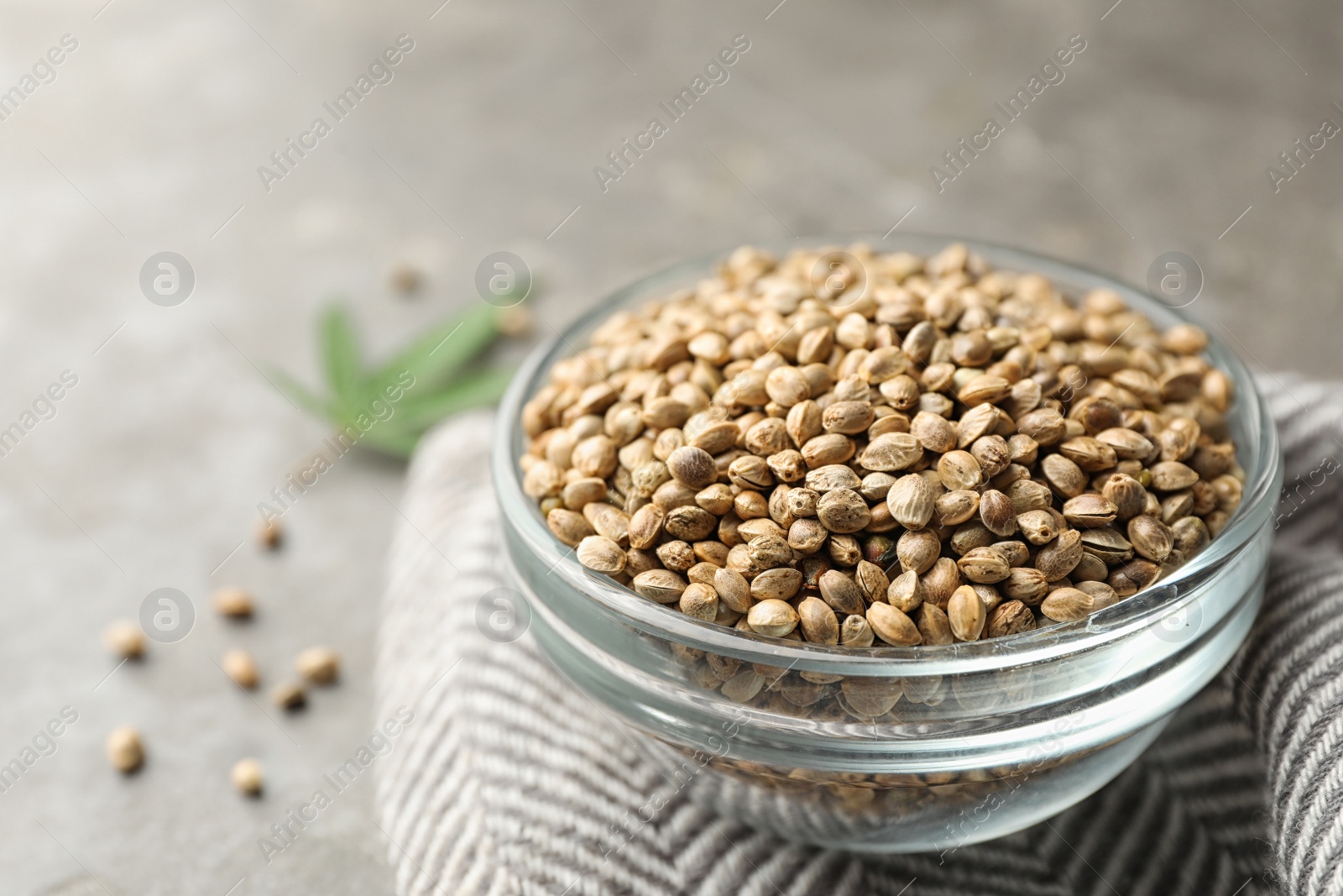 Photo of Organic hemp seeds in bowl on grey table