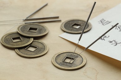 Photo of Acupuncture needles, Chinese coins and sheet with characters on paper, closeup