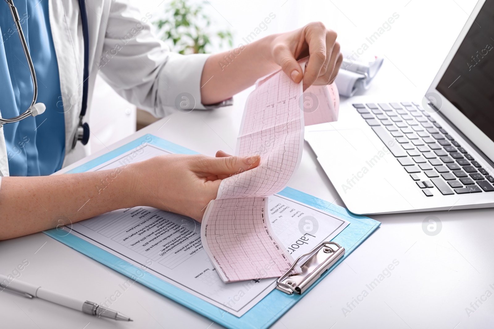 Photo of Doctor examining cardiogram at table in clinic, closeup