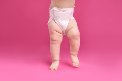 Photo of Little baby in diaper on pink background, closeup