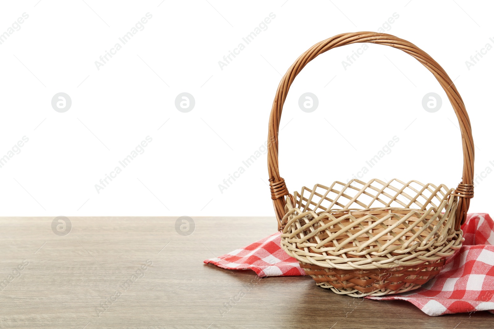 Photo of Empty wicker basket and cloth on wooden table against white background, space for text. Easter holiday