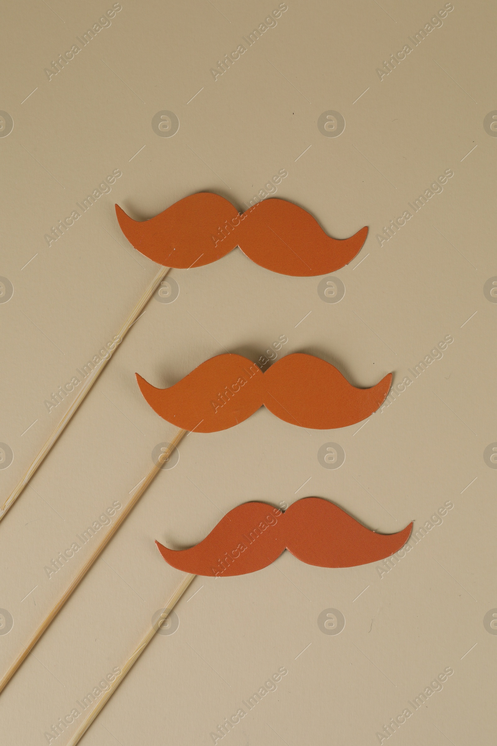 Photo of Fake paper mustaches party props on beige background, flat lay