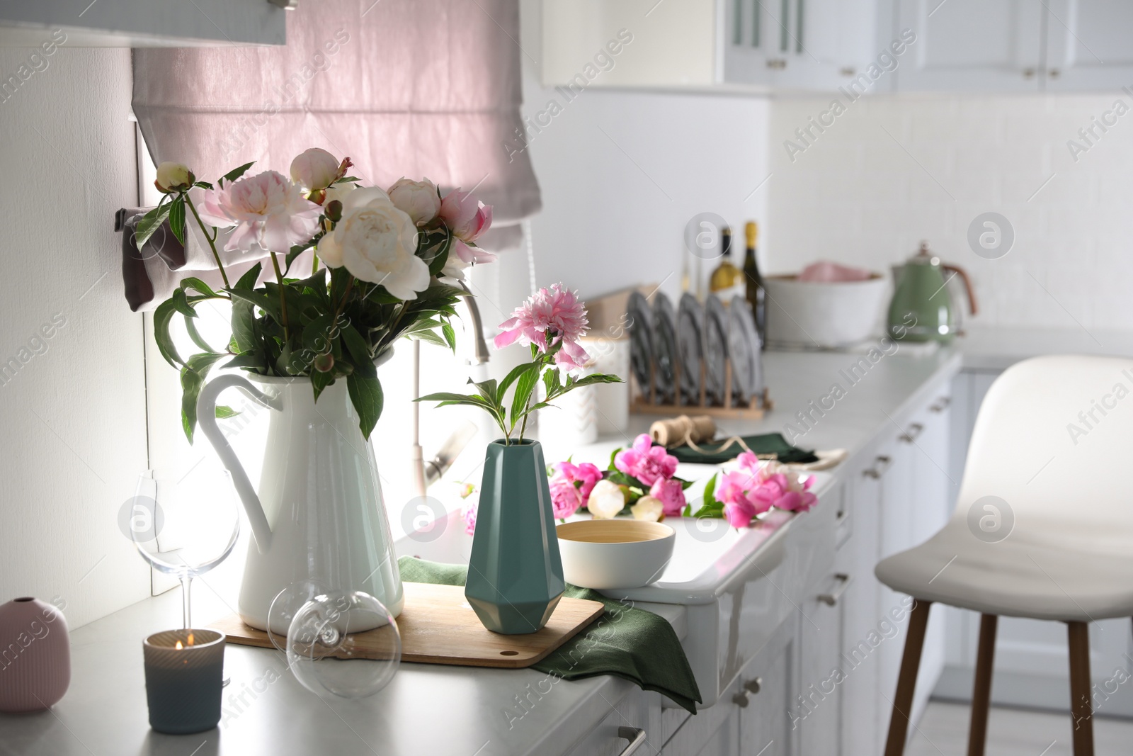 Photo of Beautiful peonies in vases on kitchen counter