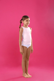 Photo of Cute little girl in underwear on pink background