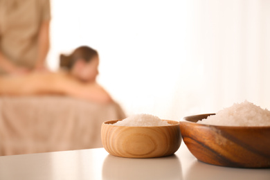 Photo of Bowls with sea salt on white table in spa salon