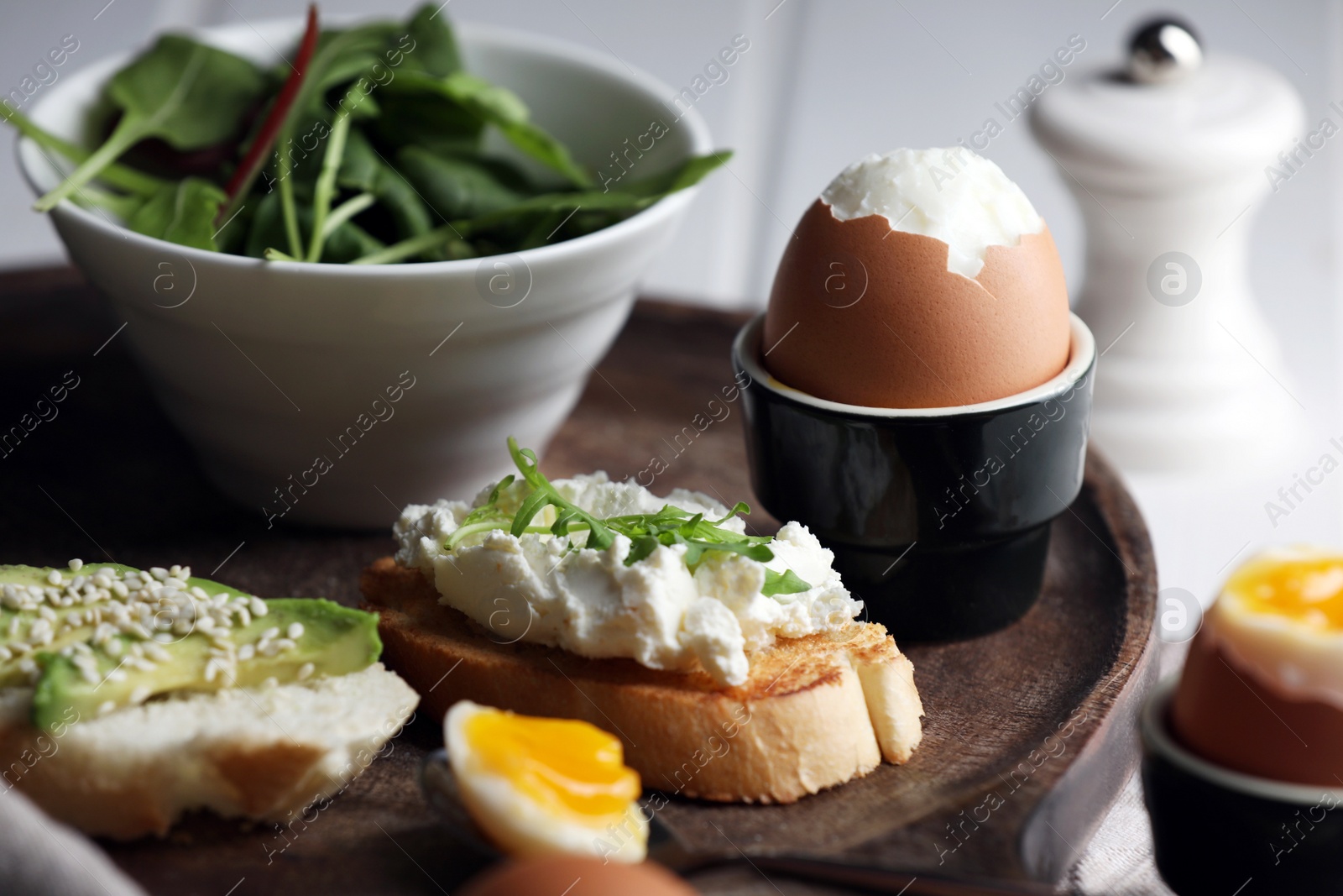 Photo of Fresh soft boiled egg in cup and sandwiches on wooden tray