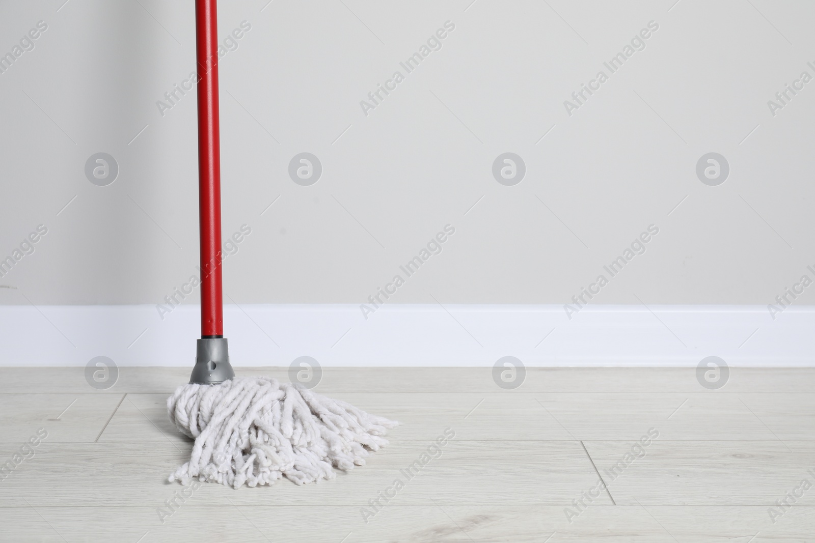 Photo of Mop with plastic handle near wall indoors. Space for text