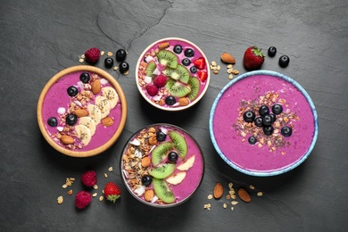 Acai smoothie bowls with granola and fruits on black table, flat lay