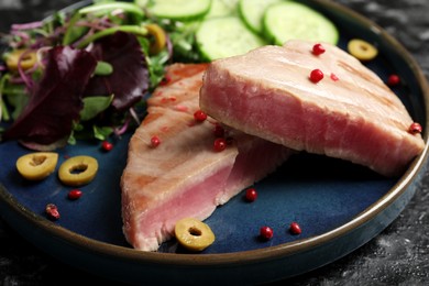 Photo of Pieces of delicious tuna with olives, salad and spices on plate, closeup