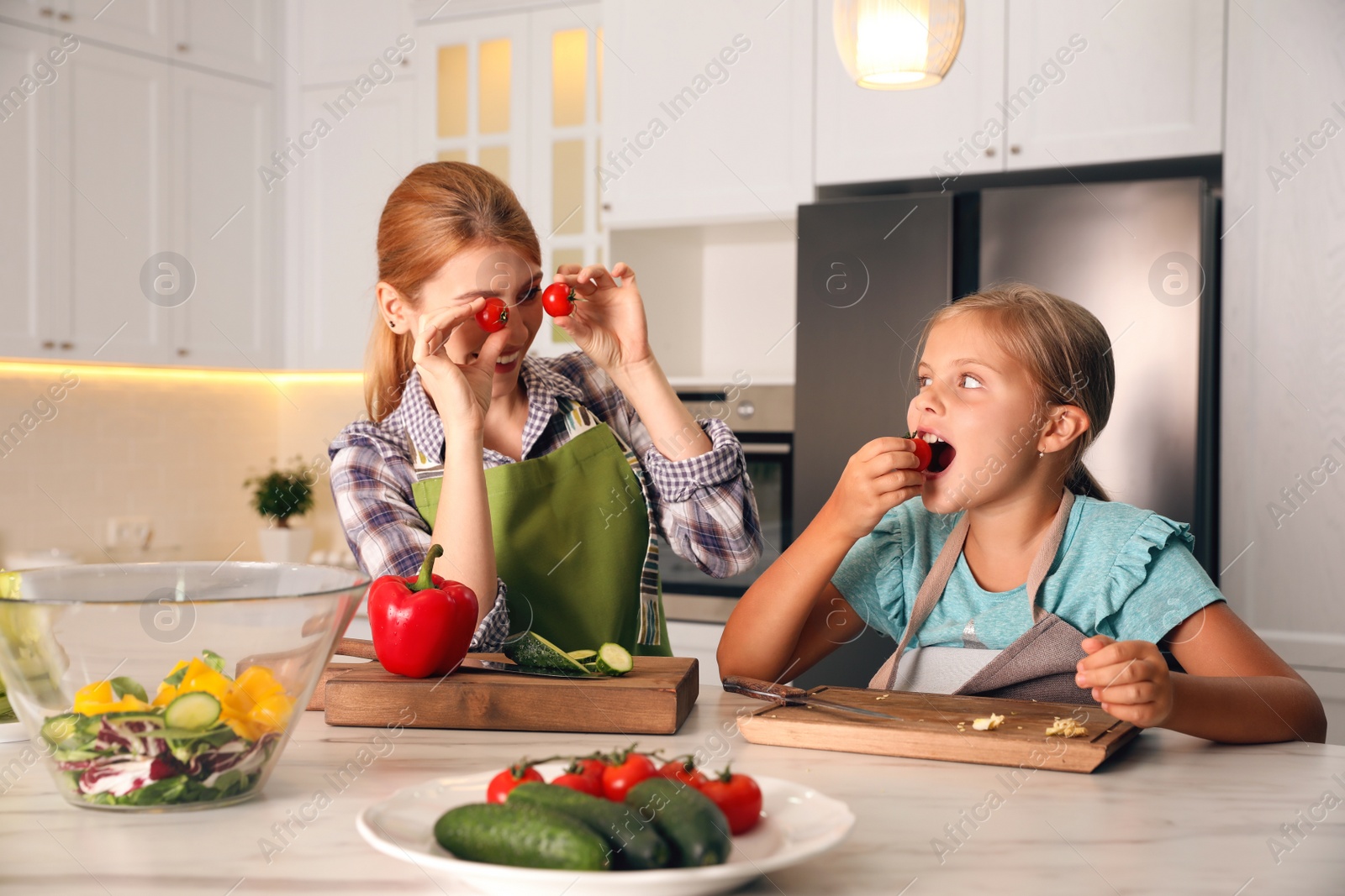 Photo of Mother and daughter cooking salad together in kitchen