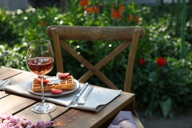 Delicious Belgian waffle with fresh strawberries and wine served on table in spring garden