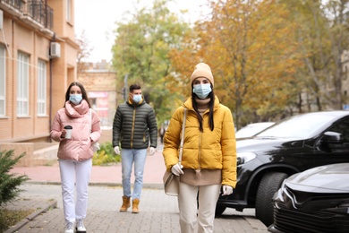 Photo of People in medical face masks walking outdoors. Personal protection during COVID-19 pandemic