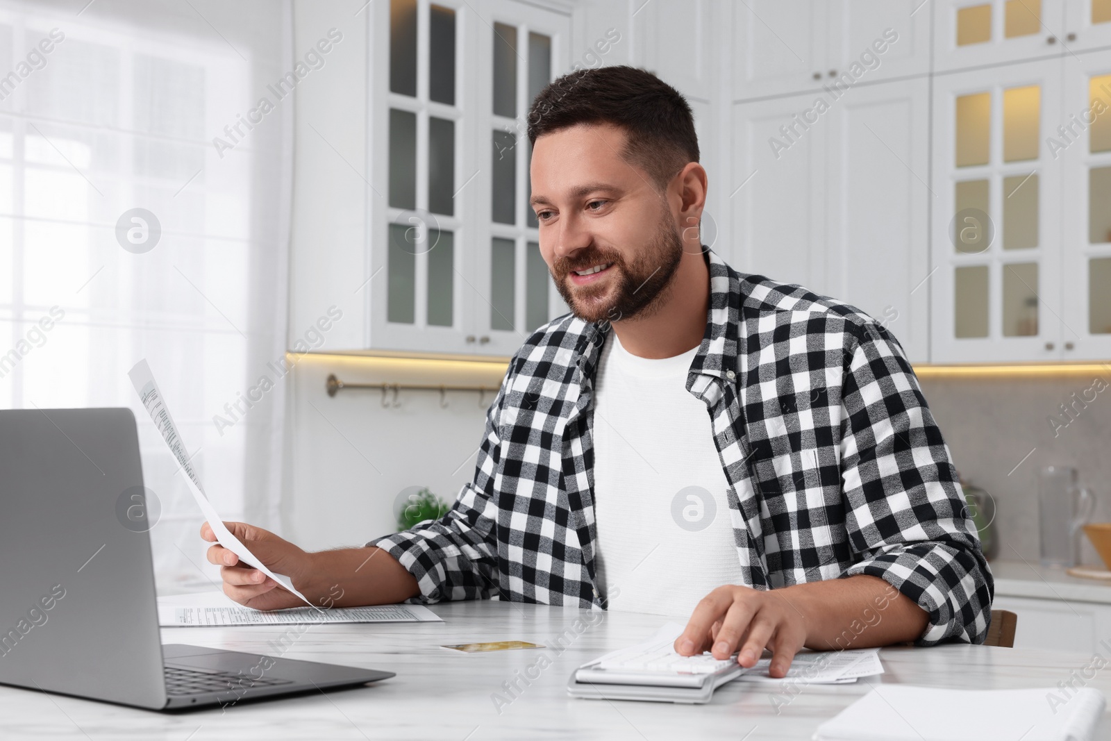 Photo of Man calculating taxes at table in kitchen