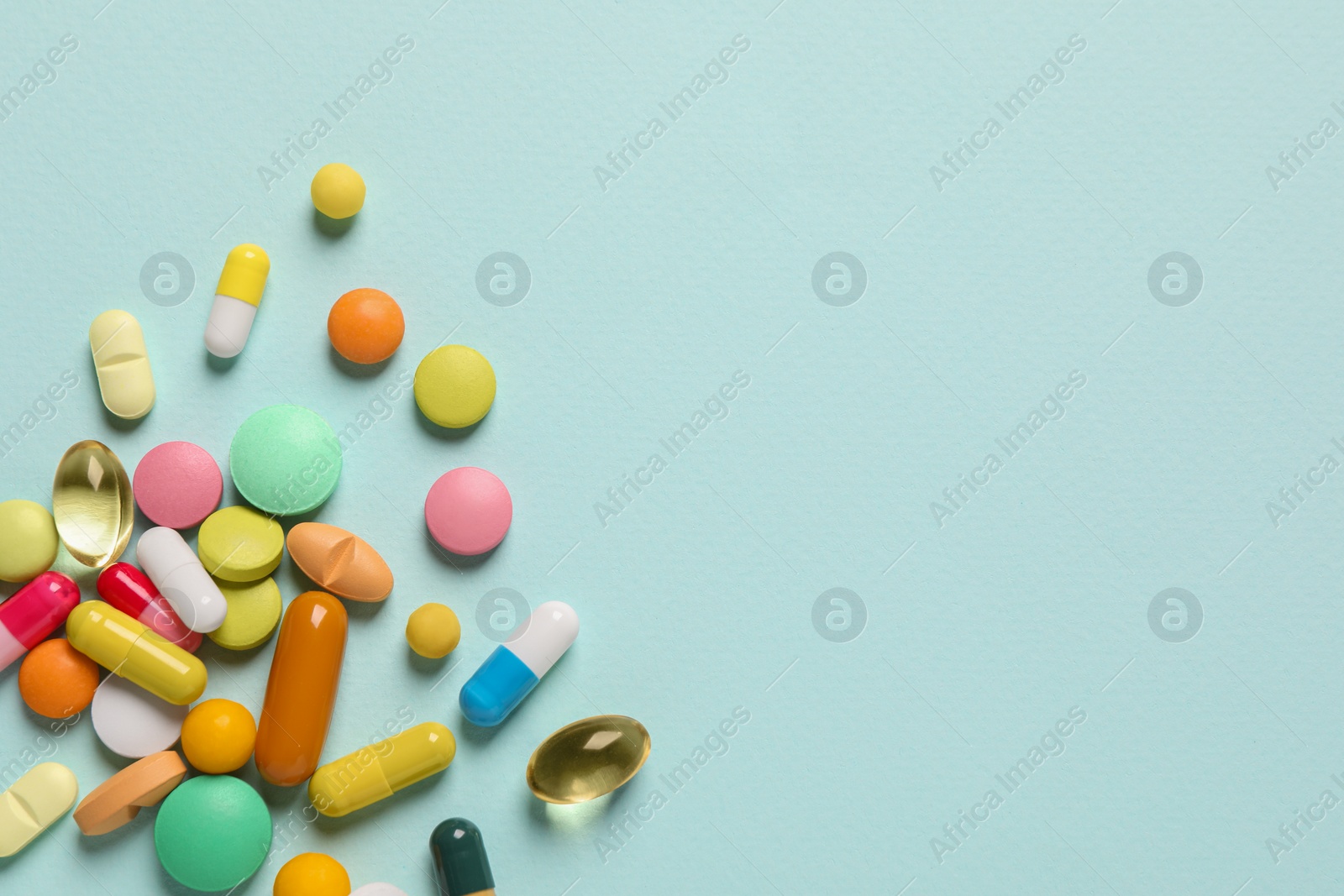Photo of Many different pills on light blue background, flat lay. Space for text
