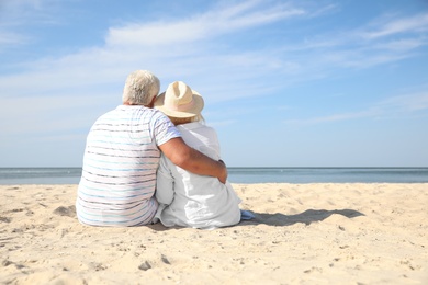 Photo of Mature couple spending time together on sea beach, back view