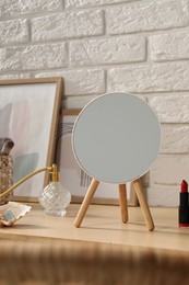 Photo of Mirror, makeup products and perfume on wooden dressing table