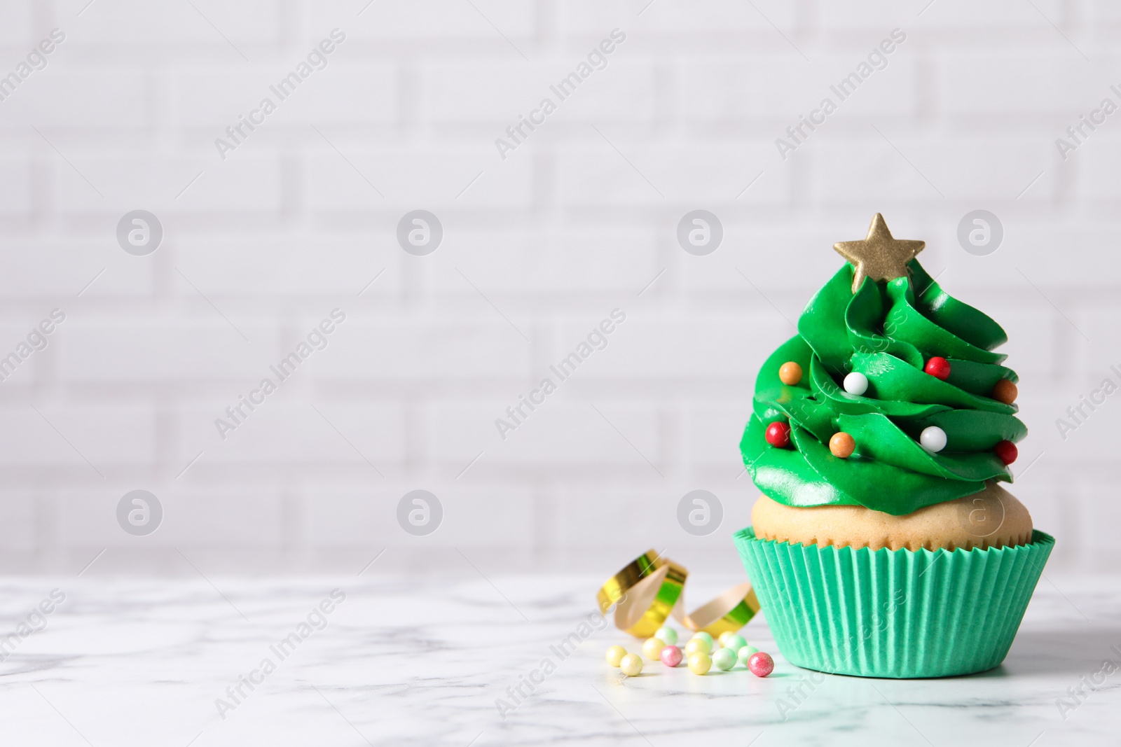 Photo of Christmas tree shaped cupcake on white marble table. Space for text
