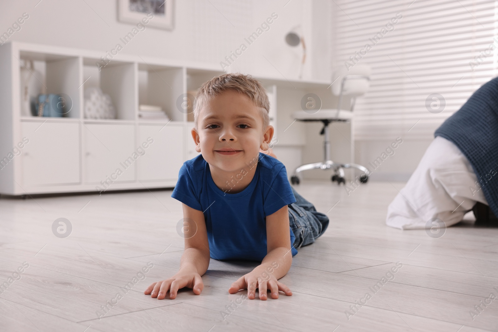 Photo of Cute little boy lying on warm floor at home. Heating system