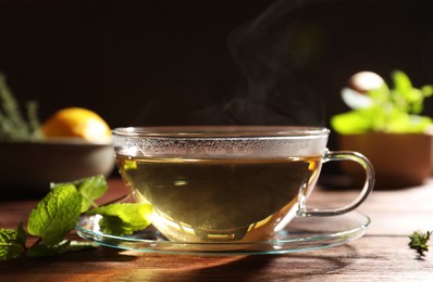 Cup of aromatic herbal tea and fresh mint on wooden table