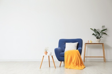 Photo of Stylish living room interior with comfortable blue armchair near white wall. Space for text