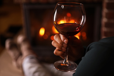 Photo of Man with glass of wine near fireplace at home, closeup