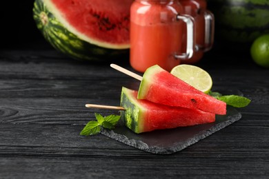 Photo of Slate board with juicy watermelon and lime on black wooden table, space for text