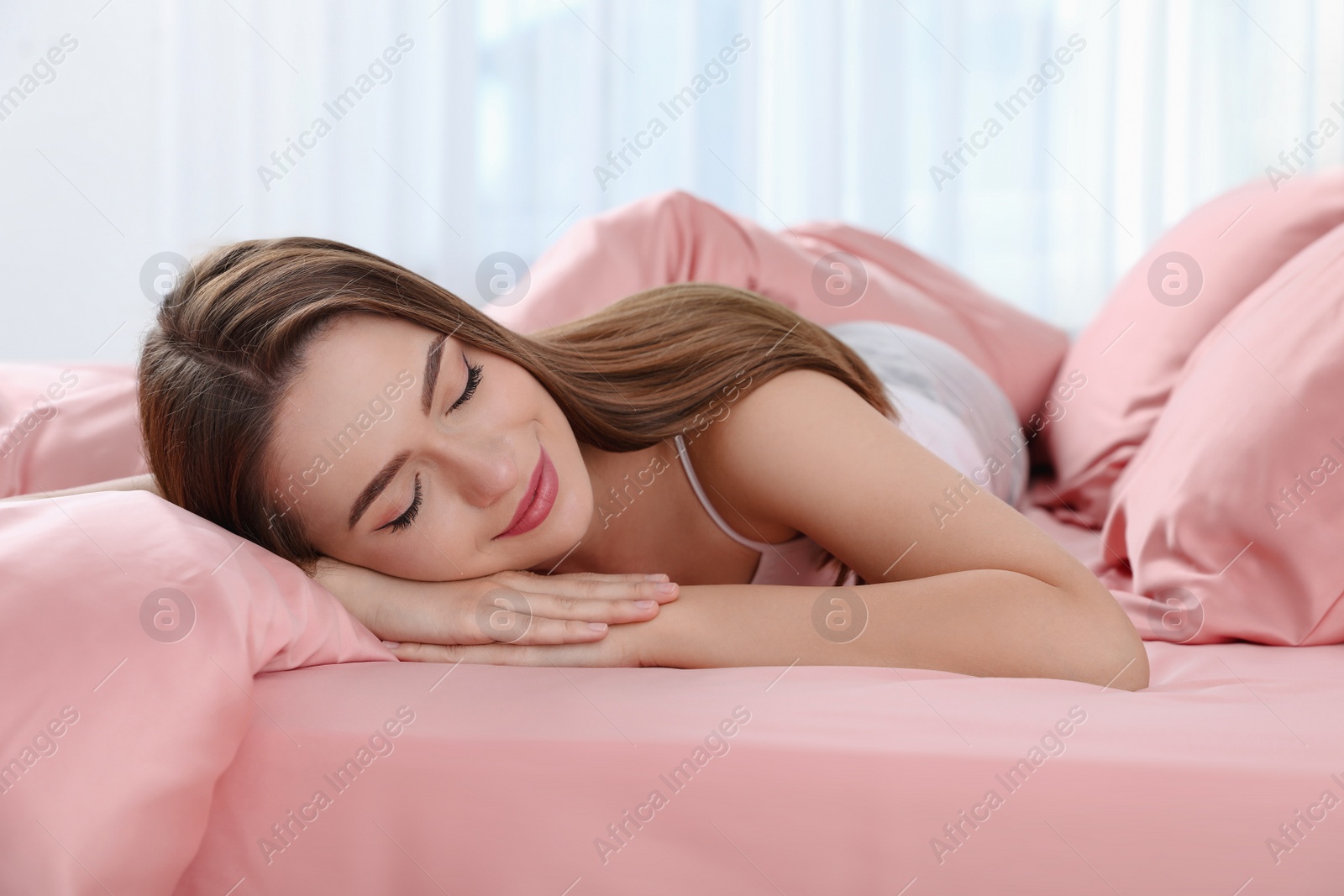 Photo of Young woman sleeping on comfortable bed with silky linens