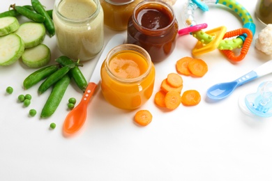 Jars with tasty baby food on white background