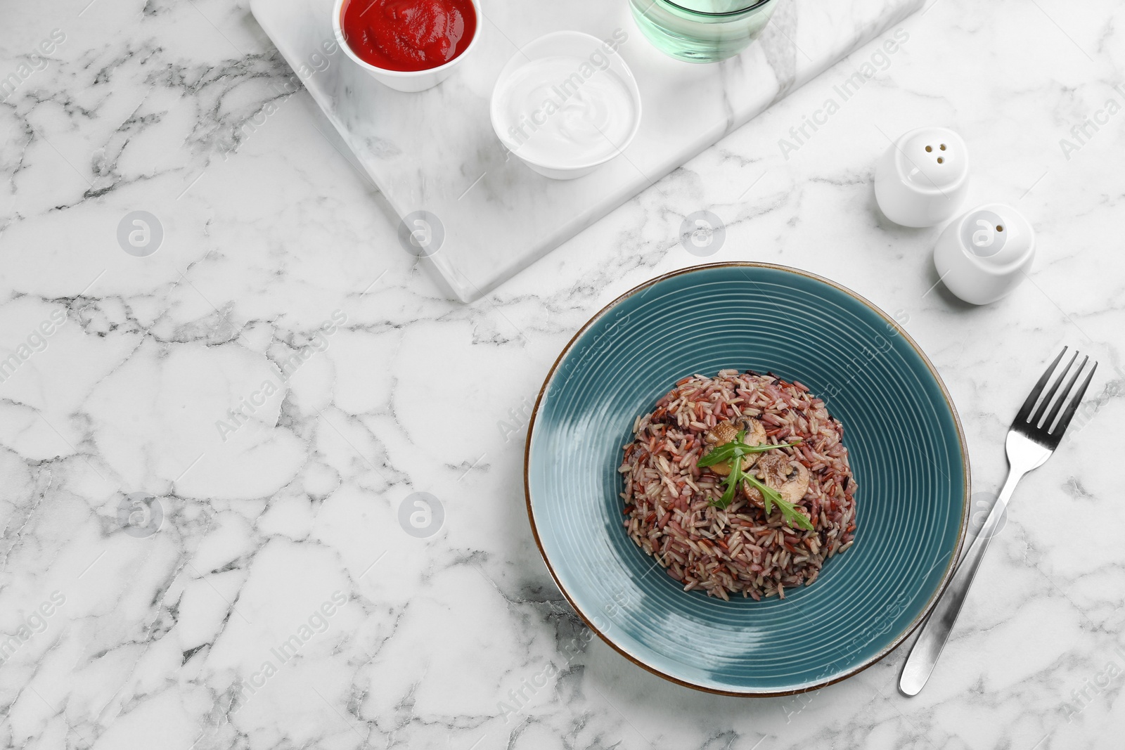 Photo of Tasty brown rice served on marble table, flat lay. Space for text