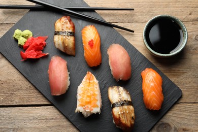 Photo of Serving board with delicious nigiri sushi and soy sauce on wooden table, flat lay