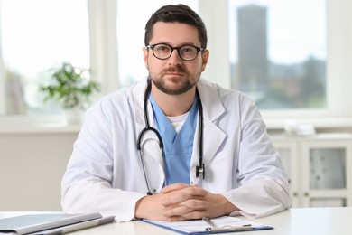 Photo of Doctor with stethoscope at table in clinic