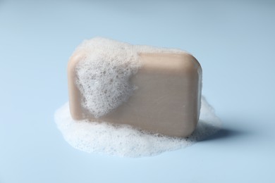 Soap with fluffy foam on light blue background