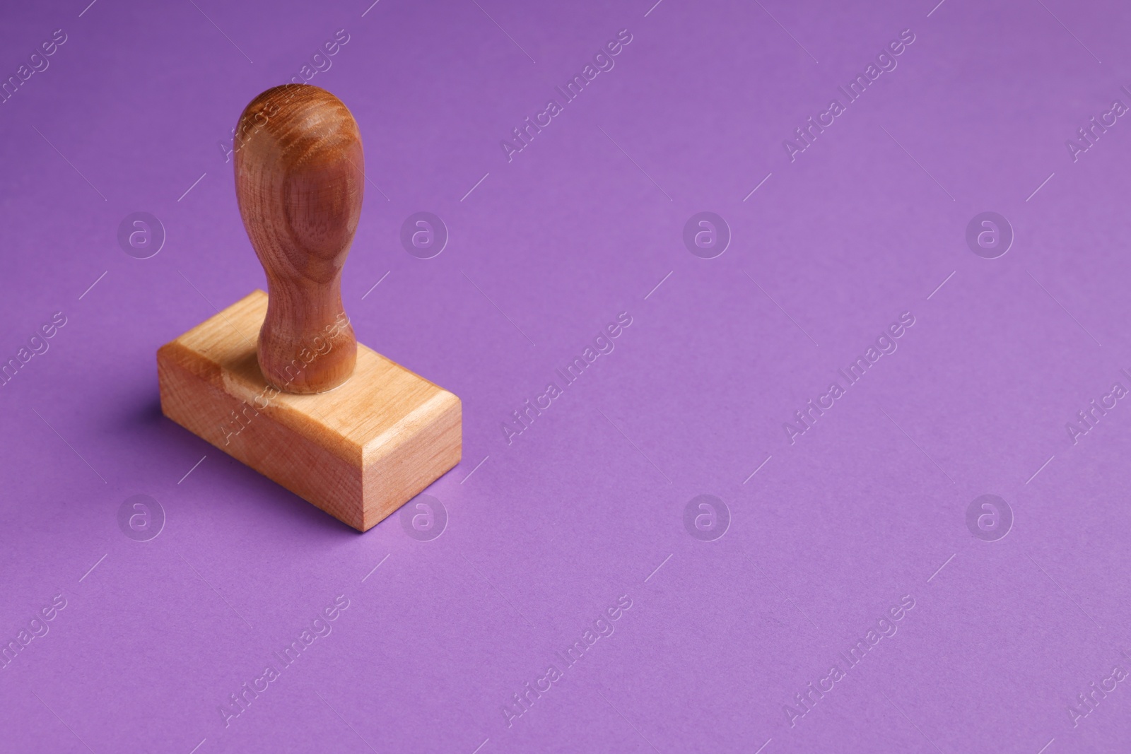 Photo of One wooden stamp tool on purple background. Space for text