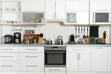 Photo of Different appliances, clean dishes and utensils on kitchen counter