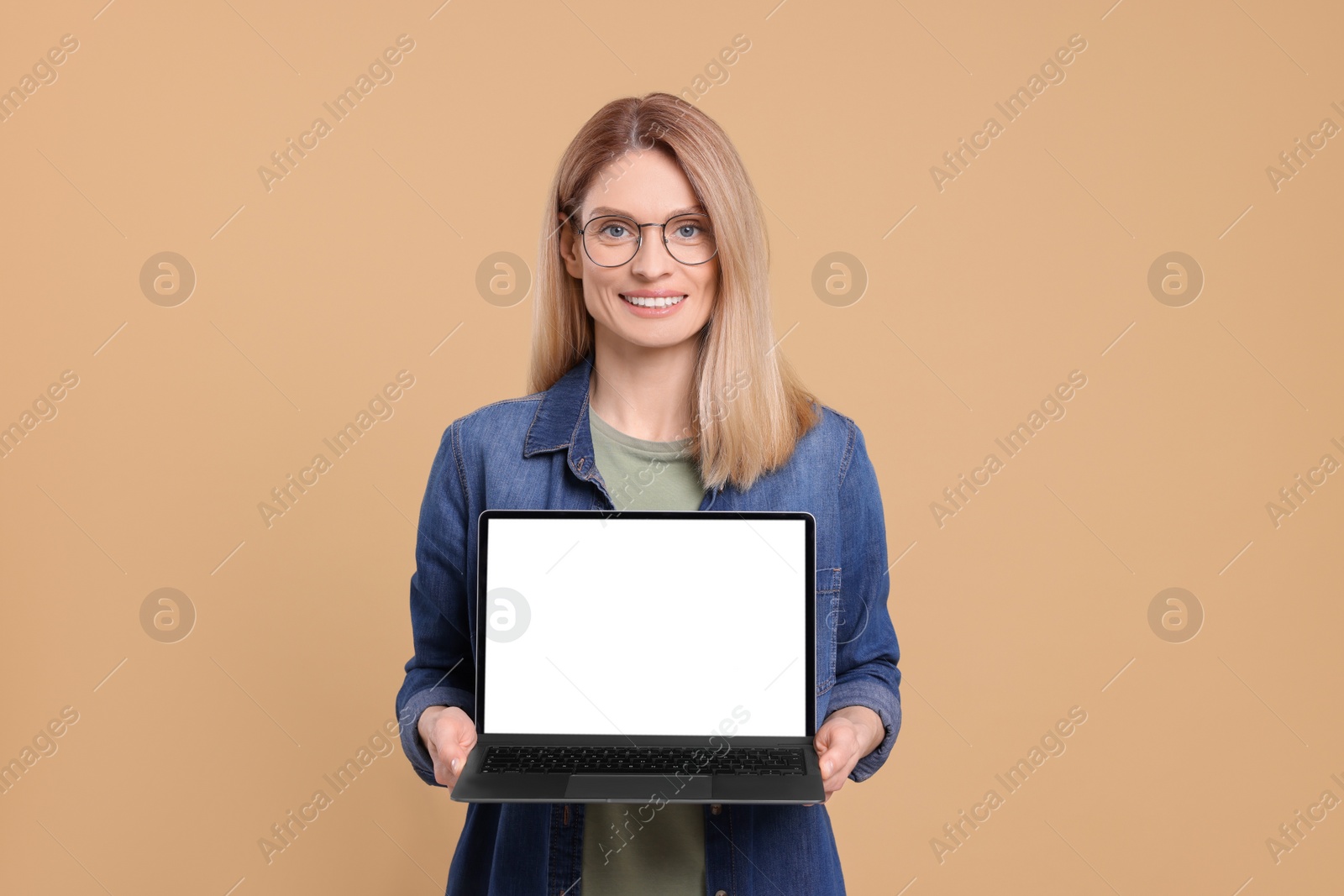 Photo of Happy woman showing laptop on beige background