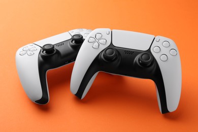 Photo of Two wireless game controllers on orange background