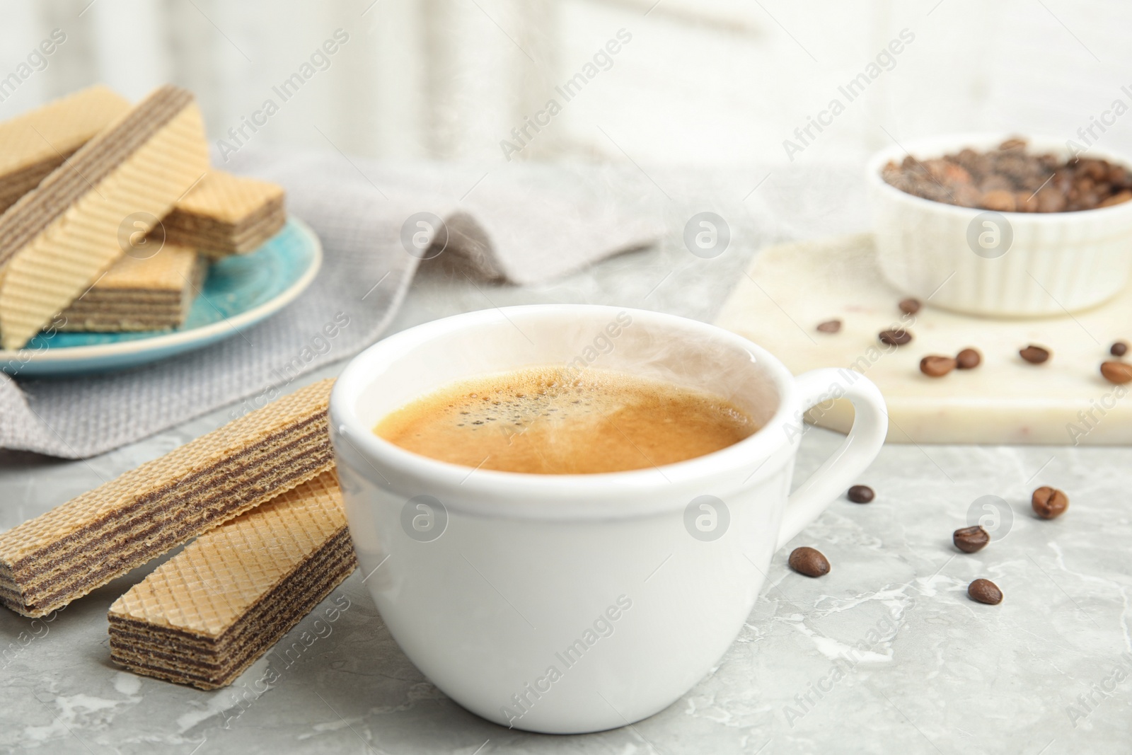 Photo of Delicious wafers and cup of coffee for breakfast on grey marble table