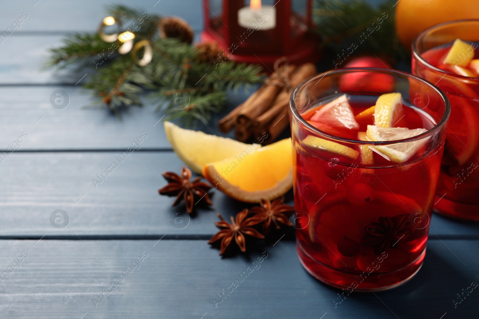 Photo of Delicious punch drink with cranberries and orange on blue wooden table. Space for text