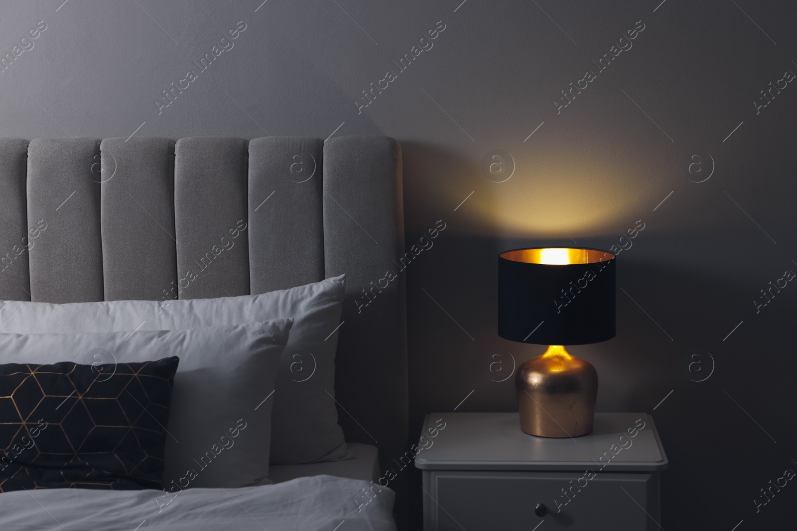 Photo of Stylish lamp on bedside table indoors. Bedroom interior element