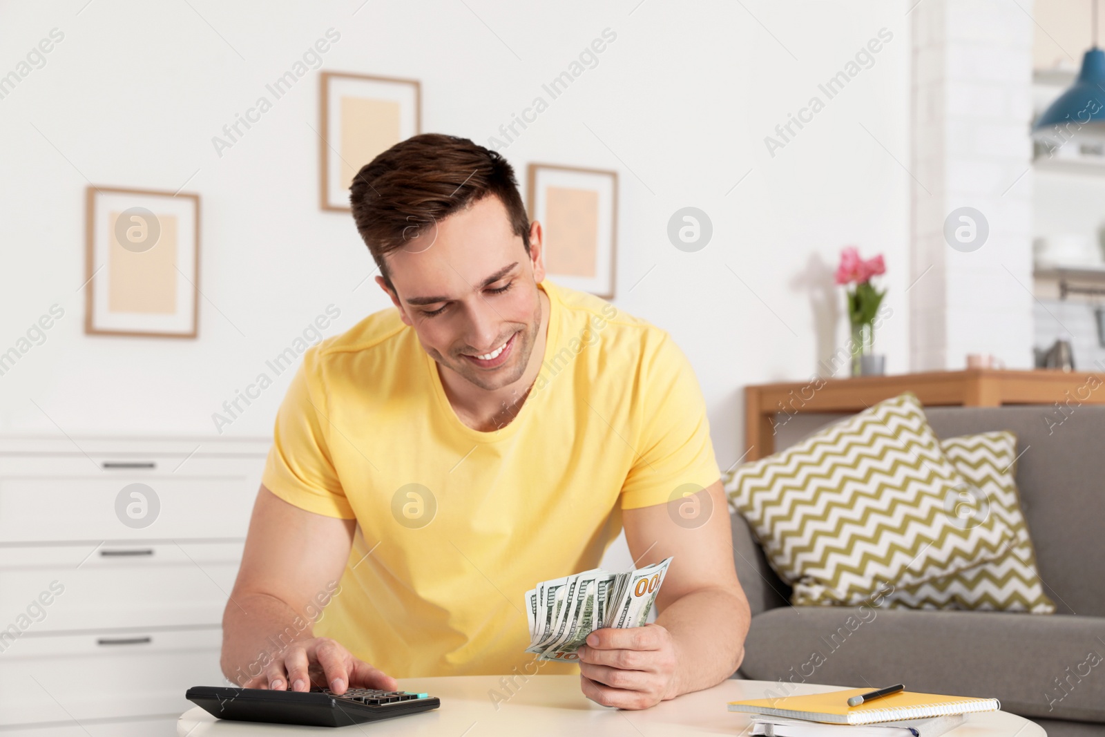 Photo of Happy man counting money at table in living room