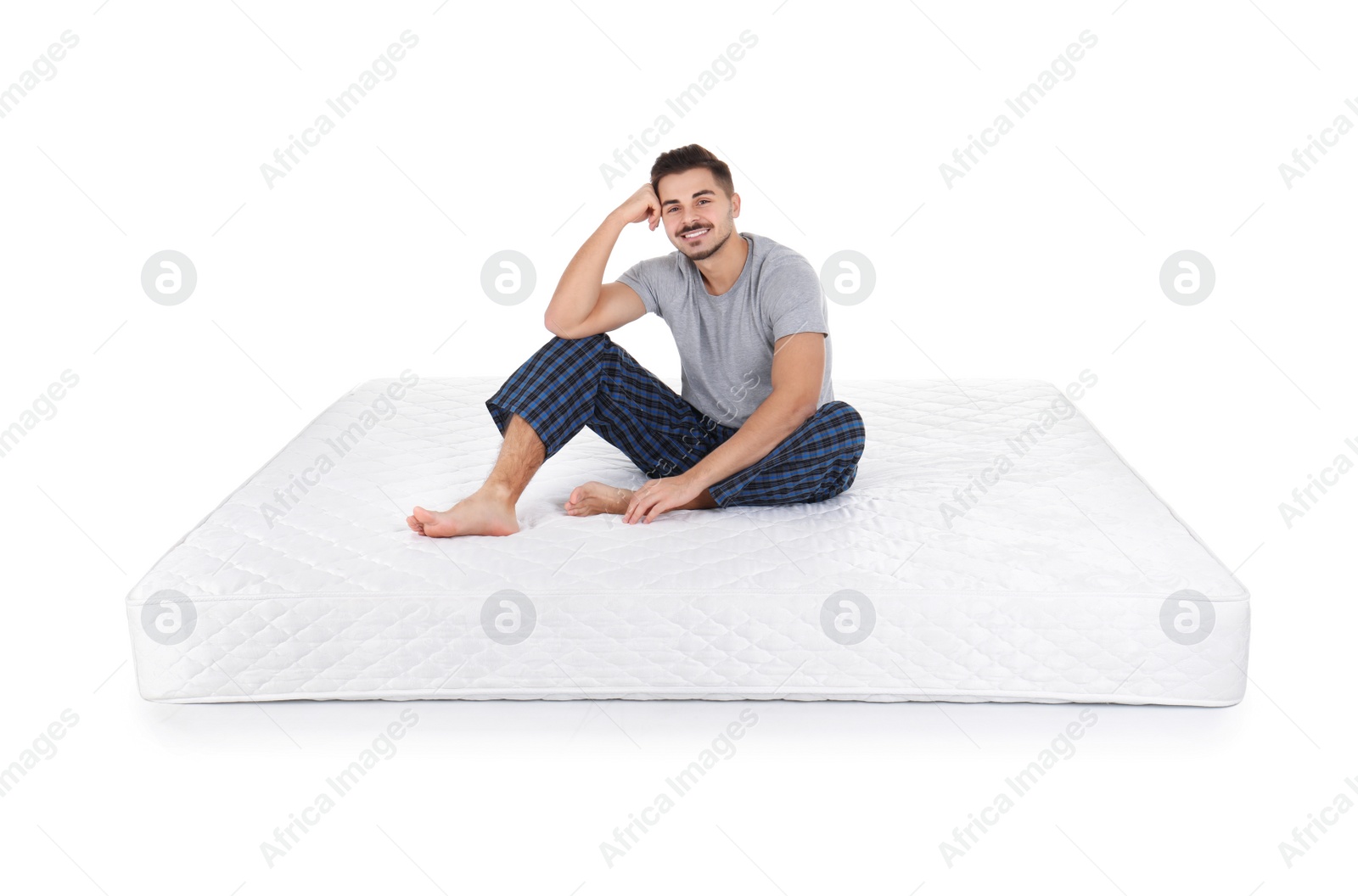 Photo of Young man sitting on mattress against white background